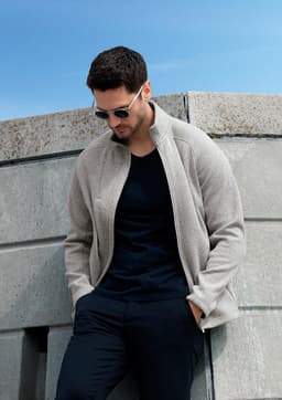 A polar fleece jacket in beige, featuring a stand-up collar and a brand logo, worn by a man.