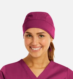 A unisex scrub cap in a vibrant purple, worn by a smiling individual with brown hair tied back.