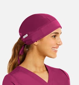 A unisex scrub cap in vibrant magenta, featuring a back tie for a secure fit and a small logo.