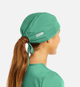 A unisex scrub cap in teal, featuring a logo, with a tie at the back for adjustable fit.