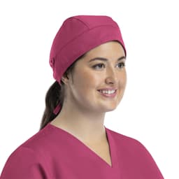 A unisex scrub cap in vibrant pink, featuring buttons, worn by a smiling woman.