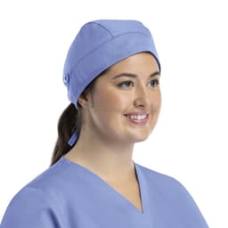 A unisex scrub cap in light blue with buttons, worn by a smiling woman.