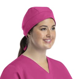 A pink unisex scrub cap with buttons displayed on a model, featuring a tied back design.