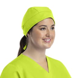 A unisex scrub cap in bright yellow with buttons, worn by a smiling woman with a ponytail.
