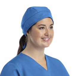A unisex scrub cap in blue, featuring buttons and worn by a smiling individual.