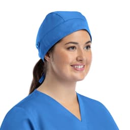 A unisex blue scrub cap with buttons, worn by a woman smiling, set against a plain background.