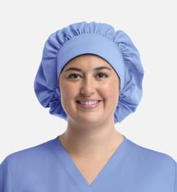 A unisex bouffant scrub cap in light blue, featuring a gathered design and soft fabric, worn by a smiling person.