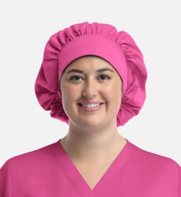 A pink bouffant cap worn by a smiling model, paired with a matching pink uniform top. The cap features a gathered design.