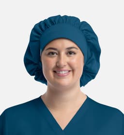 A unisex bouffant cap in teal, designed for uniforms, worn by a person smiling. The cap features a logo.