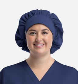 A unisex bouffant scrub cap in navy blue, featuring a gathered design and worn by a model.