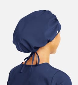 A navy unisex bouffant scrub cap with a gathered design and ties at the back. Features a logo on the side.