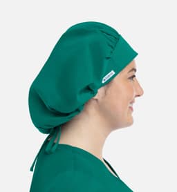 A unisex bouffant cap in green, featuring a gathered design and a side tie, worn by a model.