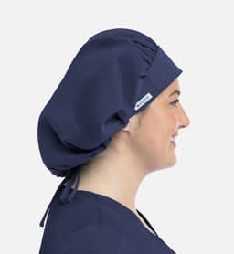 A navy unisex bouffant scrub cap displayed on a person, featuring a logo and adjustable ties at the back.
