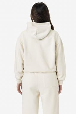 A cream-coloured garment dye plush fleece pullover hoodie with a hood, worn by a model from the back.