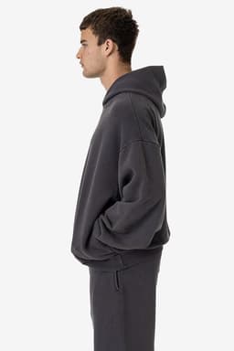 A grey garment dye plush fleece pullover hoodie on a model, featuring a relaxed fit and a hood.