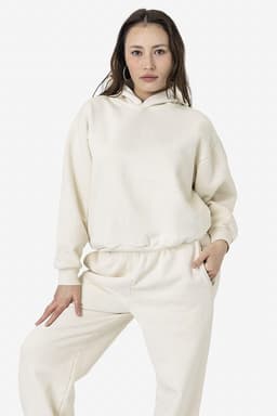 A cream-coloured plush fleece pullover hoodie with a hood and side pockets, styled with matching bottoms.