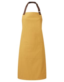 A mustard yellow bib apron with a brown leather strap and a front pocket, featuring a logo.