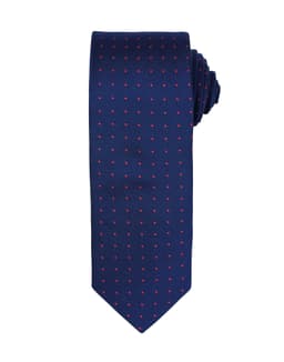 A navy tie featuring small red dots, neatly rolled. The tie includes a branding logo.