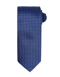 A blue tie featuring a houndstooth pattern, rolled neatly for display. It has branding on the label.
