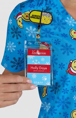 A blue printed top featuring various cartoon characters and snowflakes, with a staff name badge attached.
