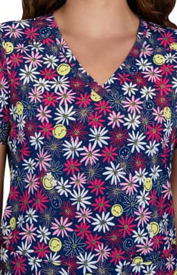A floral print scrub top featuring navy blue, pink, yellow, and white colours with a V-neck design.