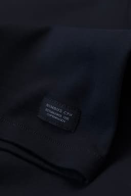 A dark blue men's t-shirt featuring a branding label on the sleeve. The fabric appears smooth and comfortable.