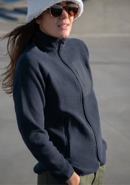 A navy women's jacket with a zip front, featuring a sleek design and side pockets, worn by a model.