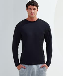 A long sleeve performance t-shirt in black, worn by a model, paired with grey pants. The shirt features a logo.