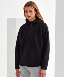 A black Sherpa 1/4-zip hoodie with a hood and a relaxed fit, modelled by a woman. Features a logo.