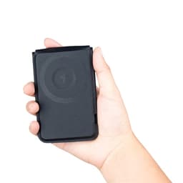 A black magnetic card wallet and wireless charging stand held in a hand. It features a logo on the surface.