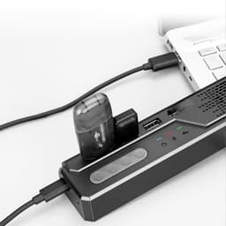 A black Akron Omnidirectional Speaker Phone connected to a laptop, featuring buttons and ports for connectivity.