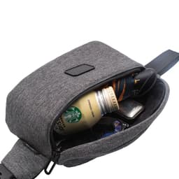 A grey anti-theft sling bag with a drink bottle, sunglasses, and a wallet visible inside.