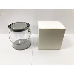 A transparent PVC bucket with a silver metal handle next to a plain white box.