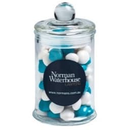 A clear apothecary jar filled with white and blue chewy fruit sweets, topped with a dome lid.