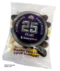A clear bag containing assorted jelly beans in black, white, and yellow, featuring a logo and a decorative label.