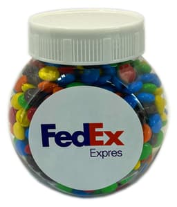 A plastic jar filled with multicoloured M&Ms, featuring a logo on the front.