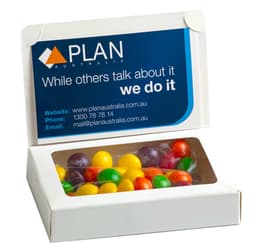 A white box containing colourful Skittles candies, featuring a branding logo on the lid.