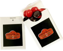 A flip lid cardboard box containing red and black choc beans, with a logo on the front.