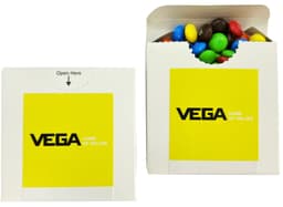 A cardboard box with a flip lid containing colourful choc beans, including blue, green, yellow, red, and brown M&Ms.
