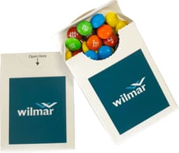 A flip lid cardboard box containing mini M&Ms in vibrant colours. The box features a logo on the front.
