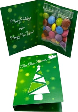 A green card featuring a Christmas tree design, containing a clear bag of colourful Smarties.