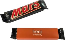 A Mars Bar wrapped in black packaging with an orange sleeve. The bar features a logo on the front.
