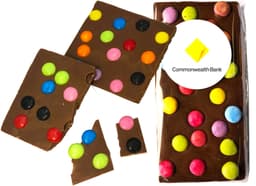 Premium chocolate bar with colourful spotty candy dots in vibrant colours on a brown chocolate background, with packaging and logo.