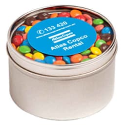 A small round tin filled with colourful M&Ms, featuring a blue label and a silver finish.
