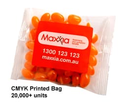 A clear bag containing orange jelly beans, with a logo on the packaging.