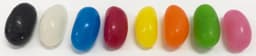 A row of jelly beans in various colours, including black, white, blue, red, yellow, orange, green, and pink.