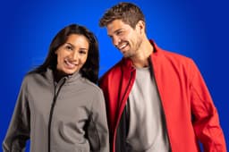 A grey soft shell jacket and a red soft shell jacket are worn by two models against a blue background.