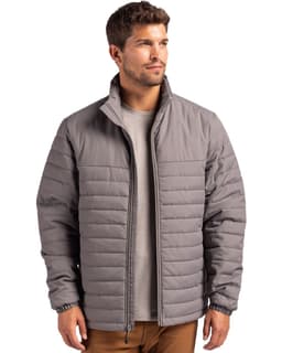 A man wearing a grey puffer jacket with a zip front and standing against a plain background.