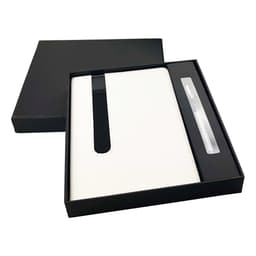 A white notebook with a black band and a pen, presented in a sleek black gift box.
