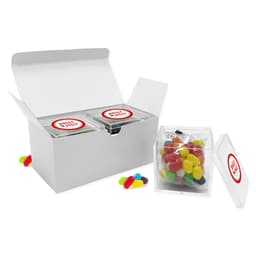 A white gift box containing two clear containers of colourful jelly beans, with additional jelly beans beside the box.